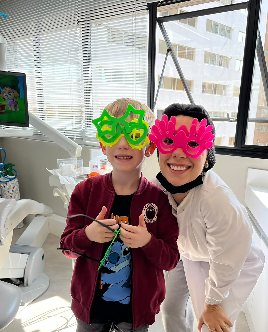 Paciente e dentista sorrindo com óculos divertidos no consultório