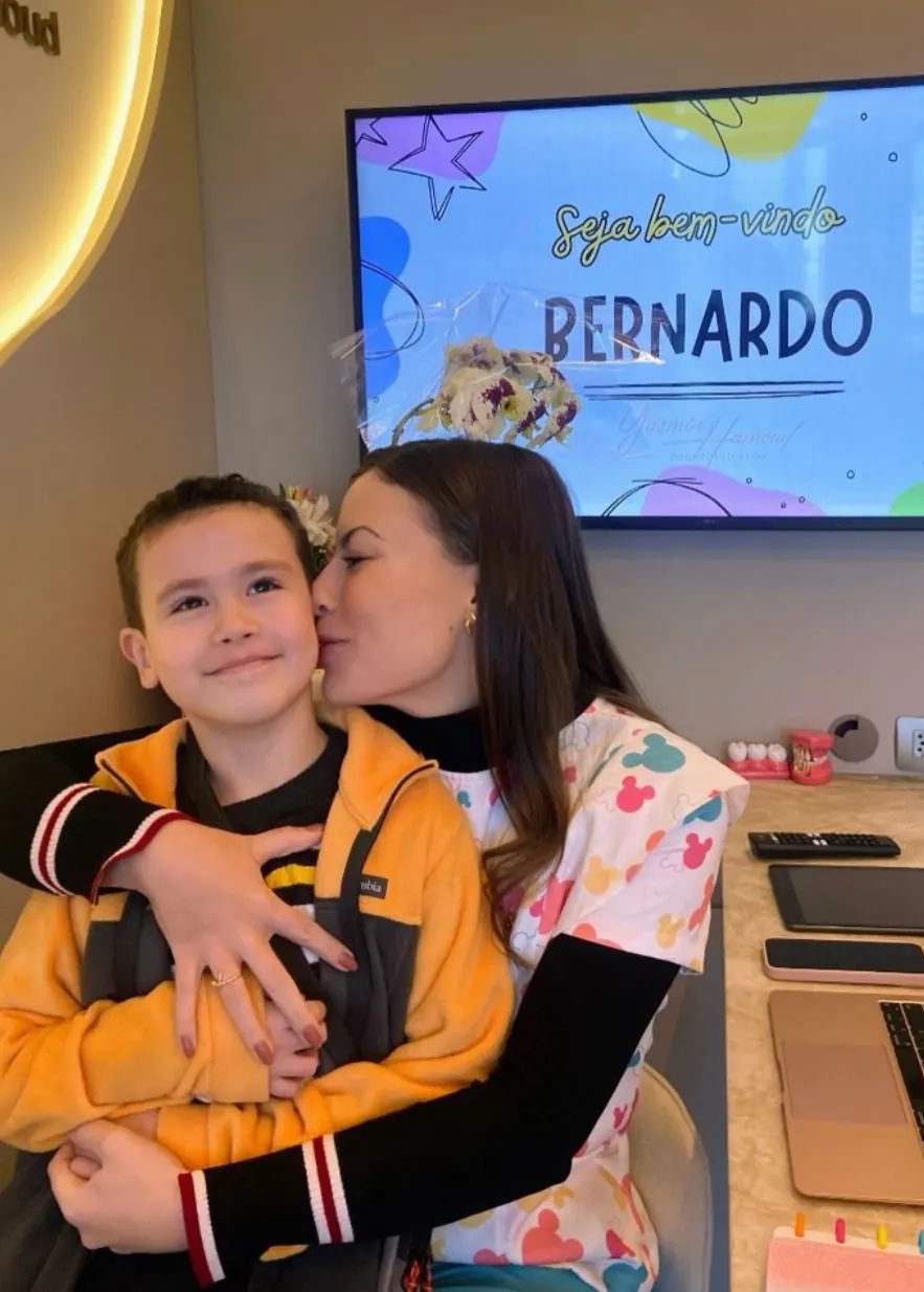 Dentista abraçando paciente com tela de boas-vindas personalizada